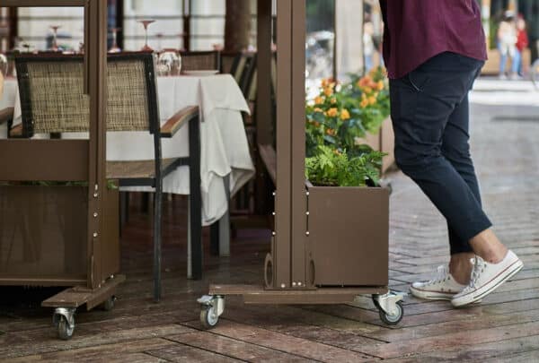 Paraviento de cristal para hostelería con ruedas movido por un camarero
